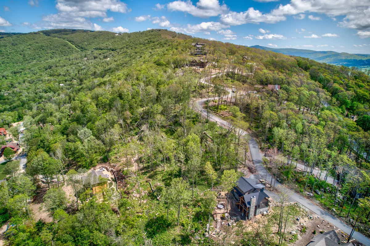 A wide shot of the mountainous terrain with scattered homes and a winding road captures the expansive, natural surroundings of the community. The open space and visible trails evoke the pet-friendly and adventure-ready character of the area.