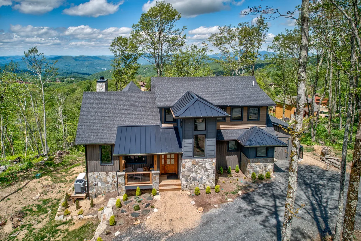 The exterior highlights a modern home with a stone façade set against a mountain backdrop. The inviting porch and surrounding natural landscape suggest a peaceful environment for family meals, morning coffee, or simply relaxing together after a day of adventures.